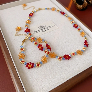 Détail d'un ensemble de collier et bracelet floral avec pétales de fleurs rouge et orange