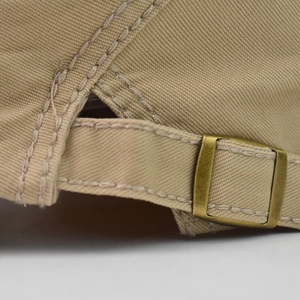 Macro shot of khaki cotton flat cap featuring adjustable metal buckle and stitching