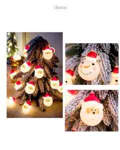 Detail of Santa and snowman Christmas string lights on a snowy tree with warm LED glow