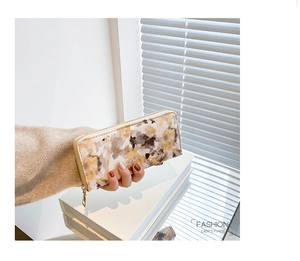 Detailed close-up of marble pattern long wallet for women with golden zipper hardware