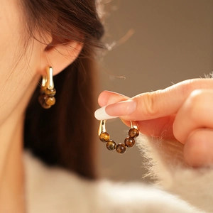 Detailed macro view of gold-plated hoop earrings featuring five brown tiger eye beads