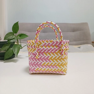 Detail of pink and yellow woven gift basket with dual handles in a cozy home setting