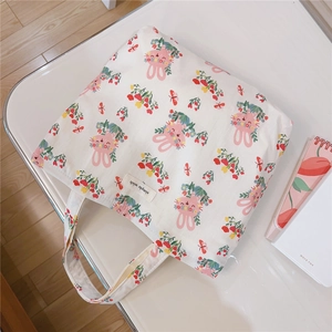 Detailed view of white canvas tote bag with pink rabbit print and simple wish label