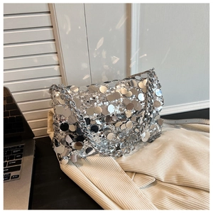 Macro shot of silver sequins on a flap shoulder bag reflecting bright metallic light