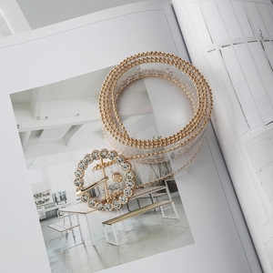 Detail of transparent PVC belt with gold bead edges and sparkling rhinestone round buckle