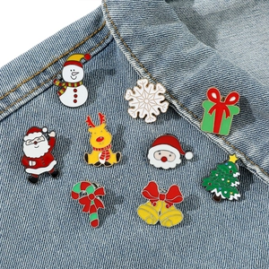 Detail of Christmas enamel pins on denim, including Santa, elk, and snowman motifs