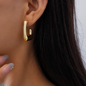 Close-up of a minimalist golden U-shaped earring worn on a model's earlobe