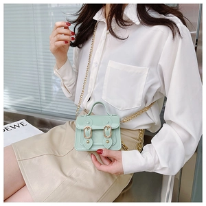Detail of mint green Cambridge bag with golden chain strap worn with casual outfit