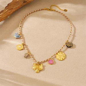 Detail of gold leopard head pendant and multi-element charms on a braided cord necklace