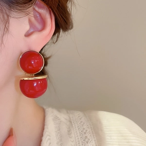 Gros plan de boucles d'oreilles perles rouges vintage avec détails dorés sur l'oreille