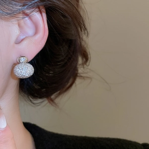 Close-up of sparkling cubic zirconia spherical stud earring worn on model's ear