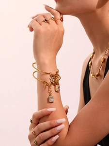 Detailed view of gold twisted bracelets and colorful gemstone rings worn by a model