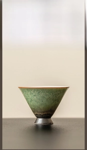 Detailed view of handmade emerald kiln-transformed ceramic tea cup with rustic glaze texture