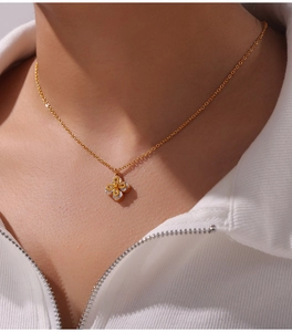 Close-up of gold clover necklace with zircon inlay on model's neck for elegant look
