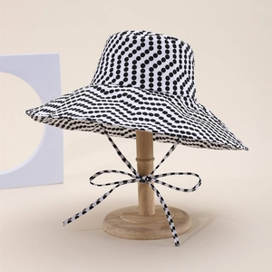 Reversible sun hat featuring black and white polka dot print with wide brim and ties
