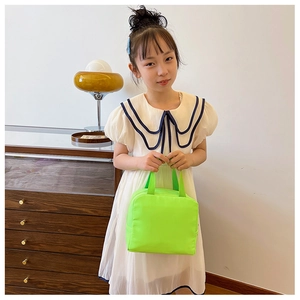 Detail of a bright green insulated tote bag held by a girl in a casual home setting