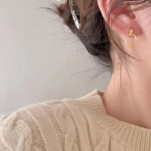 Close-up of gold geometric hoop earrings worn by a model in a cozy knit sweater