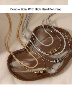 Detail of high polished double layer snake chain necklace with gold and silver beads