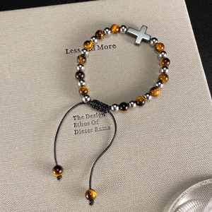 Bracciale di perle occhio di tigre con pendente a croce su uno sfondo di libro materico