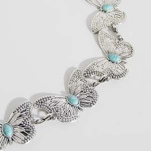 Detail of silver butterfly waist chain with turquoise stones and embossed textures