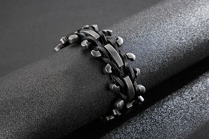 Macro view of wide braided black leather cord and textured grey industrial metal bracelet