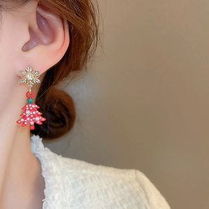 Close-up of model wearing red Christmas tree earrings with sparkling snowflake studs