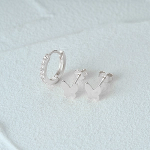 Macro shot of silver butterfly studs and zircon-set hoop earring set with S925 hallmark