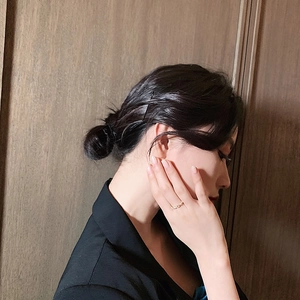 Close-up of a twisted gold adjustable ring worn by a model in a black suit