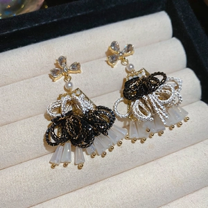 Detail shot of elegant silver needle drop earrings with crystals and pearl accents