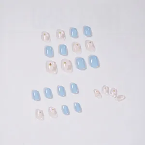 Short light blue press-on nails with white floral patterns and golden foil glitter accents