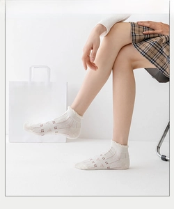Detail of white thin summer socks with lace edges and delicate small flower embroidery
