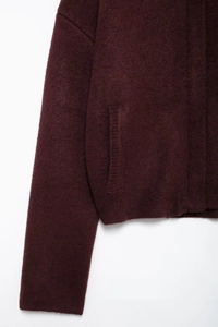 Détail de la maille bordeaux épaisse et de la poche latérale pratique du cardigan en tricot