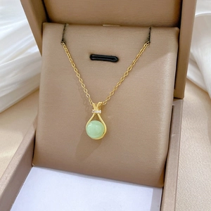 Detailed close-up of a golden drop pendant with green gemstone in a luxury jewelry box
