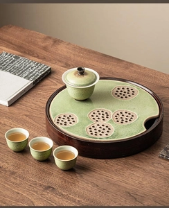 Close-up of ceramic tea set with celadon gaiwan and wooden lotus pond drainage tray