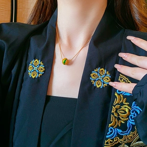 Dettaglio della collana placcata oro 18K con ciondolo in smalto verde su modella