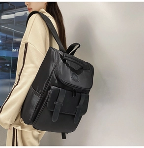 Side view of a black casual backpack with flap cover and decorative buckles on a model