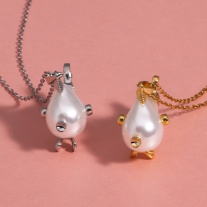 Close-up of pearl fish necklaces in silver and gold plating with crown detail