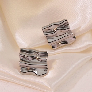 Silver square textured earrings with wavy metal design on smooth champagne satin cloth