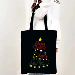 Black canvas tote bag featuring a Christmas tree graphic made of festive typography