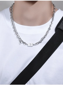 Close-up of double-layer silver zodiac necklace with rectangular tag and blue eye charm