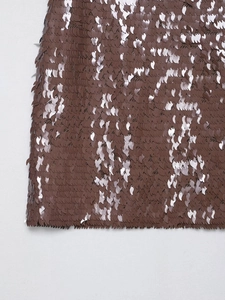 Vue macro de paillettes bronze haute densité avec coutures détaillées sur mini-jupe