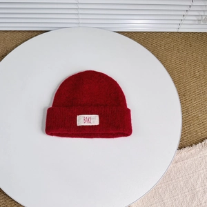 Detail of red wool knit hat showing the white fabric label and fine textured knit craftsmanship