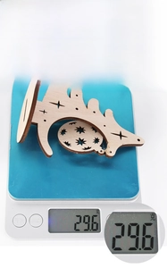 Detail of wooden Christmas tree ornament on a scale showing a weight of 29.6 grams