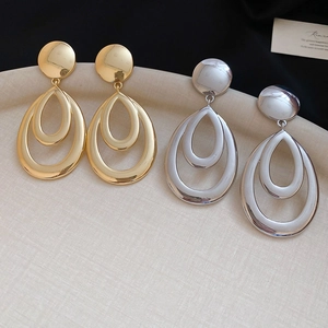 Détail de boucles d'oreilles gouttes dorées et argentées sur un plateau texturé