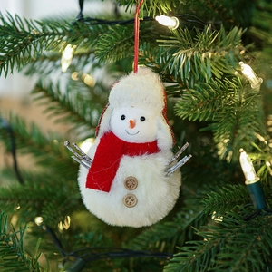 Handmade plush snowman Christmas ornament with red scarf on decorated holiday tree