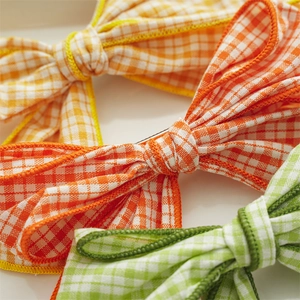Close-up of colorful plaid fabric bow hair clips in yellow, orange, and green colors