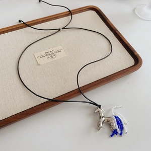 Detailed view of silver pony pendant with blue beaded fringe on black wax cord