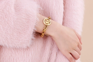 Detail of gold curb chain bracelet with diamond-encrusted couple silhouette pendant