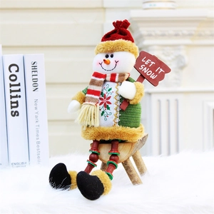 Dettaglio di un pupazzo di neve in peluche con cappello e cartello 'LET IT SNOW'