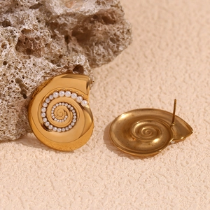Macro view of gold seashell earrings with spiral pearl inlay on textured stone